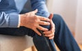 Senior man massaging his knee sitting on sofa indoor, cropped Royalty Free Stock Photo