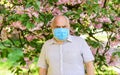 Senior man in medical mask. old man walking in park. life during coronavirus lockdown. enjoy sakura beauty. fear of