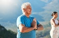 Senior man meditating with joined hands and closed eyes breathing deeply. Mature people doing yoga in nature living a Royalty Free Stock Photo