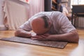 Senior man meditating on a wooden floor and lying in Shavasana pose. Royalty Free Stock Photo