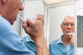 Senior man in mirror brushing his teeth Royalty Free Stock Photo