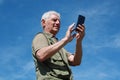 Senior man with mobile phone and blue sky background Royalty Free Stock Photo