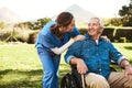 Senior man, nurse and wheelchair for support, healthcare or garden at nursing home. Happy elderly male and woman Royalty Free Stock Photo
