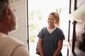 Senior man opening his front door to a female healthcare worker making a home health visit Royalty Free Stock Photo