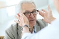 Senior man in optical store trying on eyeglasses Royalty Free Stock Photo