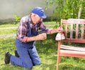 Old man painting bench in garden Royalty Free Stock Photo