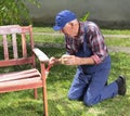 Old man painting bench in garden Royalty Free Stock Photo