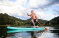 Senior man paddleboarding on lake in summer. Copy space.