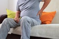 Senior man with pain in back sitting on sofa Royalty Free Stock Photo