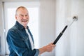 Senior man painting walls in new home, having fun. Relocation concept. Royalty Free Stock Photo