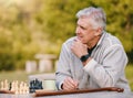 Senior man, park and thinking for chess, game and competition at table by trees, sunshine and focus. Elderly board game Royalty Free Stock Photo