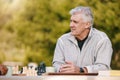 Senior man, park and thinking for chess, game and competition at table by trees, sunshine and focus. Elderly chess Royalty Free Stock Photo