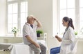 Senior man patient complaining on headache to attentive woman doctor in modern clinic hospital. Royalty Free Stock Photo