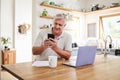 Senior man, phone and retirement budget in home kitchen for digital banking application, investment planning and fintech Royalty Free Stock Photo