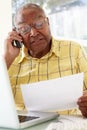 Senior Man On Phone Using Laptop At Home Royalty Free Stock Photo