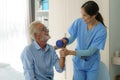 Senior man physiotherapy exercises with Asian woman caregiver or nurse physiotherapist in uniform helping aged male patient at Royalty Free Stock Photo