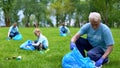 Senior man picking up litter in park together family smiling camera, earth care