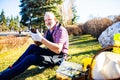 Senior man planting a plants in garden outdoors spring season ready useing a phone app Royalty Free Stock Photo