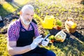 Senior man planting a plants in garden outdoors spring season ready useing a phone app Royalty Free Stock Photo