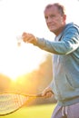 Senior man playing badminton with tennis racket in park Royalty Free Stock Photo