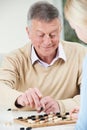 Senior Man Playing Checkers With Teenage Daughter