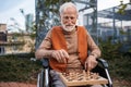 Senior man playing chess outdoors alone. Nursing home client, enjoying a game of solitaire chess. Royalty Free Stock Photo