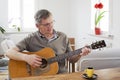 Senior man playing guitar at home in a bright living room Royalty Free Stock Photo