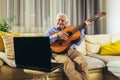 Senior man playing guitar using laptop for online lessons Royalty Free Stock Photo