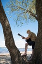 Senior man playing guitar while standing on big tree at riverside Royalty Free Stock Photo