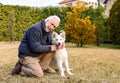 Senior man playing with White Swiss Shepherd puppy in the garden Royalty Free Stock Photo