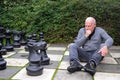 Senior man plays chess with giant chess pieces