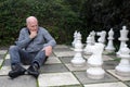 Senior man plays chess with giant chess pieces