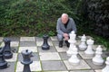 Senior man plays chess with giant chess pieces