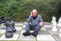 Senior man plays chess with giant chess pieces