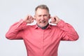 Senior man in red shirt plugging ears with fingers Royalty Free Stock Photo