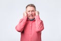 Senior man in red shirt plugging ears with fingers Royalty Free Stock Photo