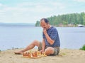 Senior man pondering a move in a game of chess and sitting on the beach near the lake Royalty Free Stock Photo