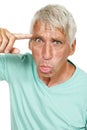 Senior man, portrait and crazy face in studio for comic, funny and comedy with finger pointing on head. Elderly person Royalty Free Stock Photo