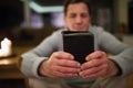 Senior man praying, holding Bible, burning candles behind him Royalty Free Stock Photo