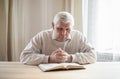 Senior man praying, reading  an old Bible in his hands Royalty Free Stock Photo