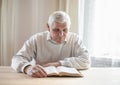 Senior man praying, reading  an old Bible in his hands Royalty Free Stock Photo