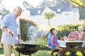 Senior man preparing barbecue while family having meal Royalty Free Stock Photo