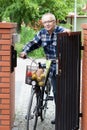 Senior man pushing bike through the gate