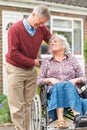 Senior Man Pushing Disabled Wife In Wheelchair Royalty Free Stock Photo