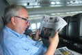 Senior man on Quantas flight from Australia to the US reading Australian newspaper Brisbane Queensland Australia circa November 20