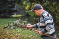 Senior man raking leaves from lawn in garden Royalty Free Stock Photo