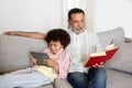 Senior Man Reading Book While Grandson Using Digital Tablet Indoor Royalty Free Stock Photo