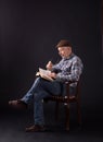 Senior man reading book on old chair Royalty Free Stock Photo