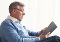 Senior Man Reading Book Sitting On Couch At Home Royalty Free Stock Photo