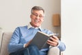 Senior Man Reading Book Sitting On Sofa At Home Royalty Free Stock Photo